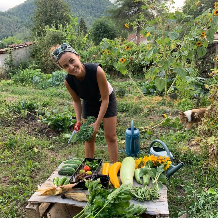 Marion Roques, chef nomade en cuisine végétale, souriant dans son jardin potager. 