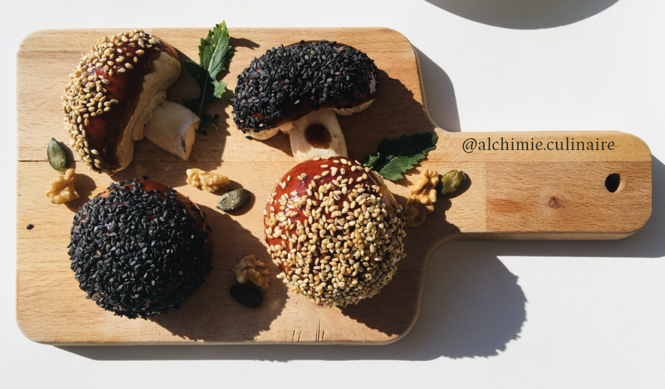 Planche forestière: Champignons croquants sauce teriyaki en croûte de sésame. Quatre champignons arrangés sur une planche en bois. Exemple de cuisine végétale. 
